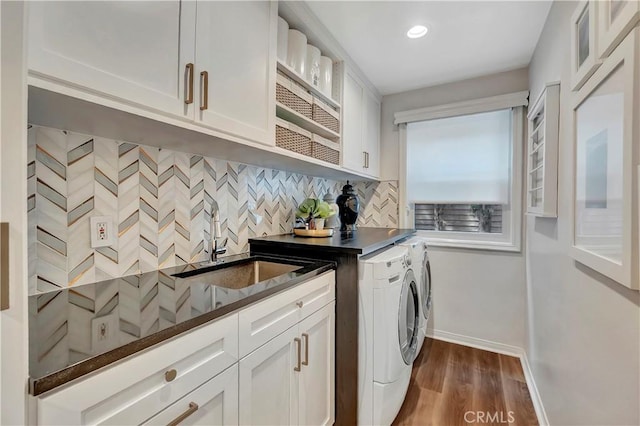 clothes washing area with dark wood-style flooring, cabinet space, a sink, baseboards, and washer and dryer