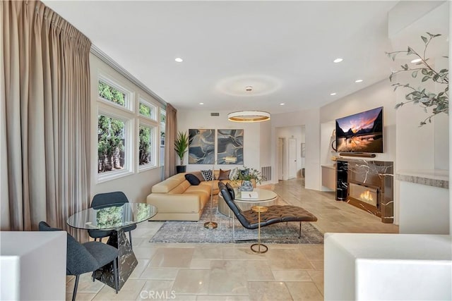 living room with recessed lighting and a warm lit fireplace