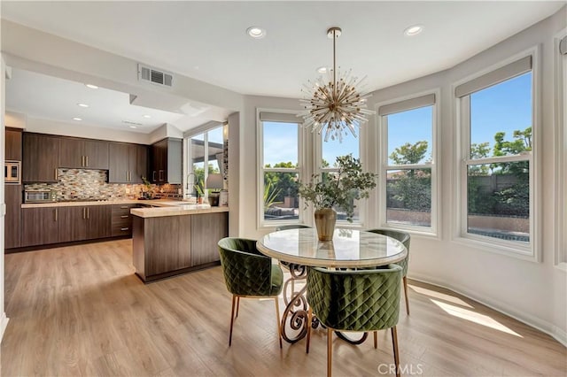 dining area with visible vents, light wood-style floors, and a healthy amount of sunlight