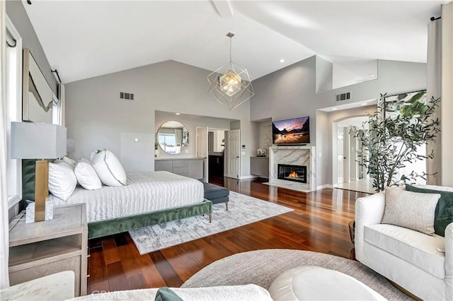 bedroom with visible vents, a high end fireplace, wood finished floors, and high vaulted ceiling