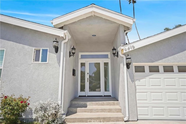 property entrance with a garage and stucco siding