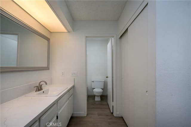 bathroom with vanity, baseboards, toilet, and wood finished floors