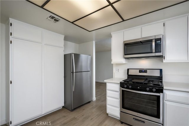kitchen featuring appliances with stainless steel finishes, white cabinetry, and visible vents