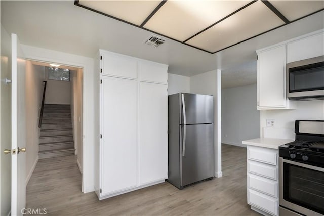 kitchen with white cabinetry, appliances with stainless steel finishes, light wood finished floors, and visible vents