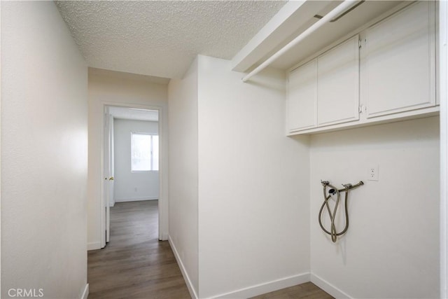 clothes washing area with wood finished floors, baseboards, hookup for a washing machine, a textured ceiling, and cabinet space