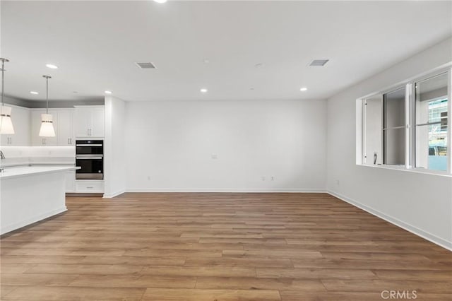 unfurnished living room featuring light wood-style floors, recessed lighting, baseboards, and visible vents