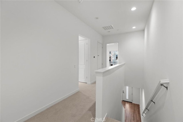 hallway with visible vents, light carpet, baseboards, recessed lighting, and an upstairs landing