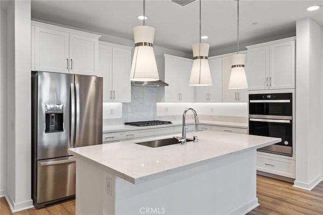 kitchen featuring gas cooktop, multiple ovens, stainless steel fridge with ice dispenser, a sink, and light wood finished floors