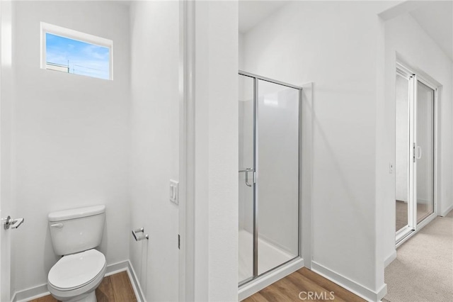 bathroom with toilet, baseboards, a shower stall, and wood finished floors