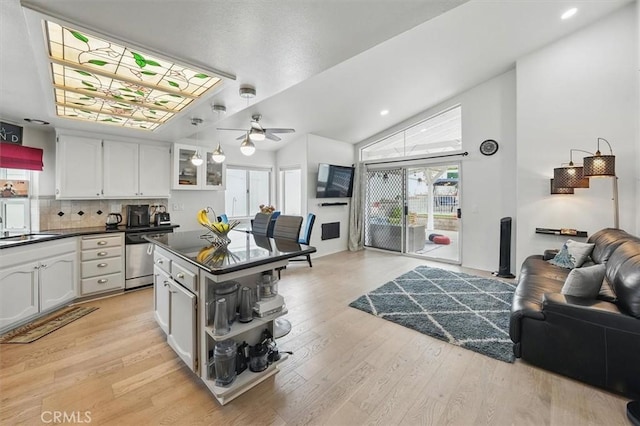 kitchen with stainless steel dishwasher, dark countertops, open floor plan, ceiling fan, and white cabinets