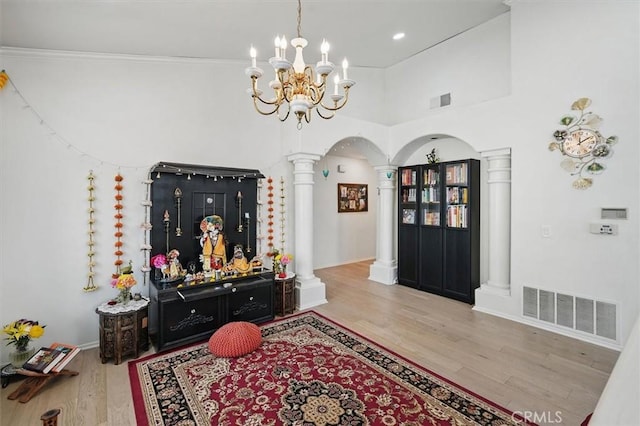 entryway with visible vents, wood finished floors, ornate columns, a chandelier, and arched walkways