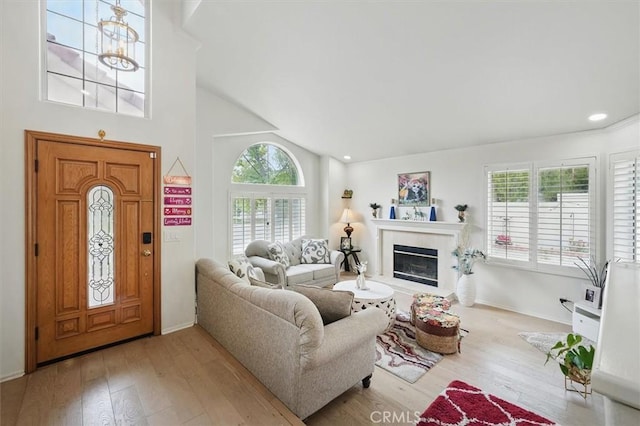 living area with wood-type flooring, baseboards, a tiled fireplace, and high vaulted ceiling