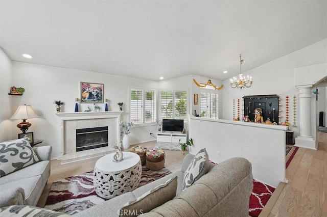 living area with recessed lighting, a notable chandelier, light wood-style flooring, and a tile fireplace