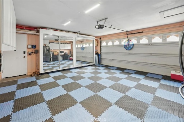 garage with a garage door opener and black refrigerator with ice dispenser