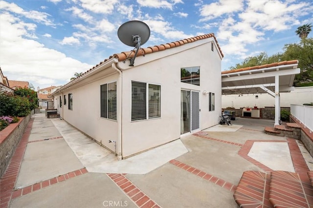 rear view of property featuring a fenced backyard, a patio, stucco siding, and a tile roof