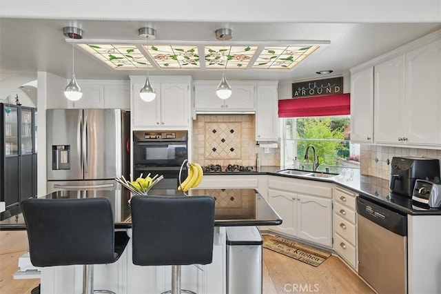 kitchen featuring dark countertops, white cabinetry, a sink, backsplash, and stainless steel appliances