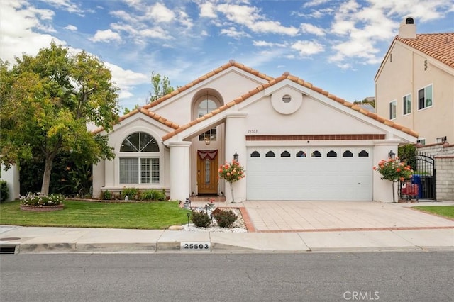 mediterranean / spanish-style home featuring a garage, a front yard, stucco siding, a tiled roof, and concrete driveway