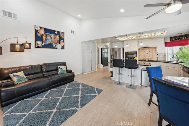 living area featuring light wood-type flooring, recessed lighting, ceiling fan, and visible vents