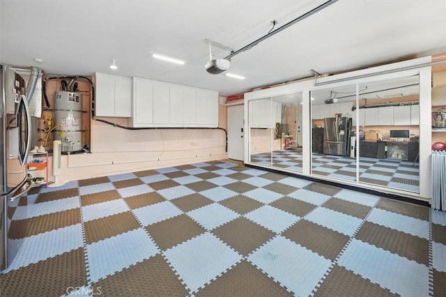 garage with freestanding refrigerator, strapped water heater, stainless steel fridge, and a garage door opener