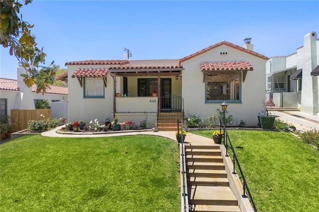 mediterranean / spanish-style home with a front lawn, stucco siding, and a tile roof