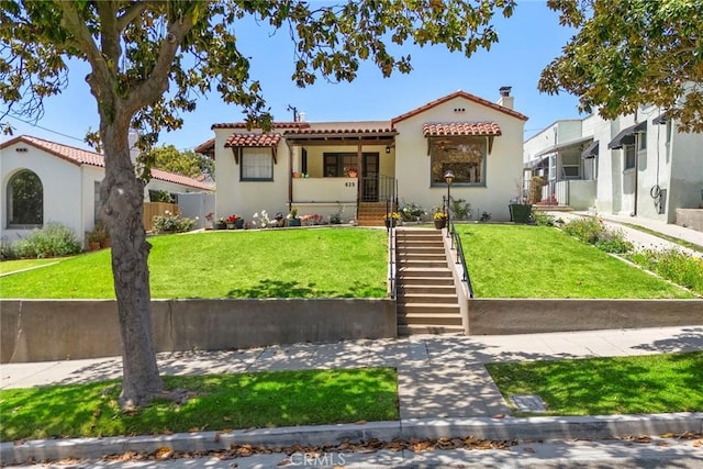 mediterranean / spanish-style home featuring fence, stairs, a front lawn, stucco siding, and a tiled roof