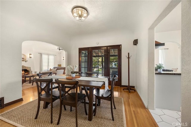 dining area featuring arched walkways, a wealth of natural light, and a fireplace