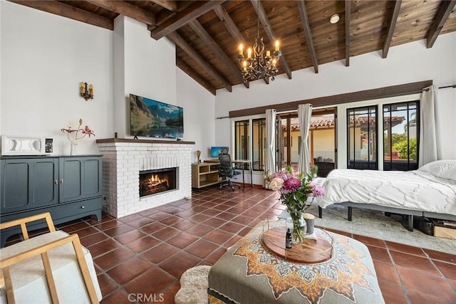 bedroom featuring an inviting chandelier, beam ceiling, a fireplace, dark tile patterned floors, and wood ceiling