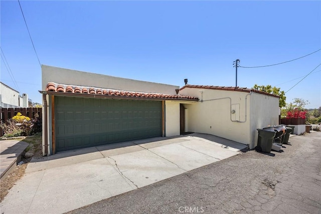 view of front of house featuring a garage, fence, stucco siding, and a tile roof