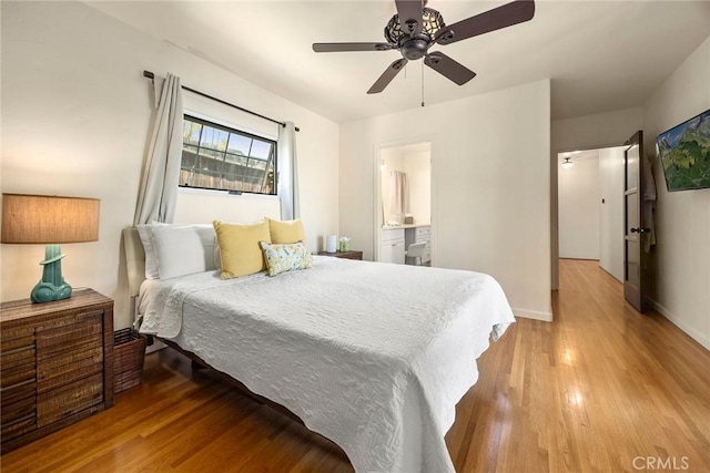 bedroom with baseboards, ceiling fan, wood finished floors, and connected bathroom