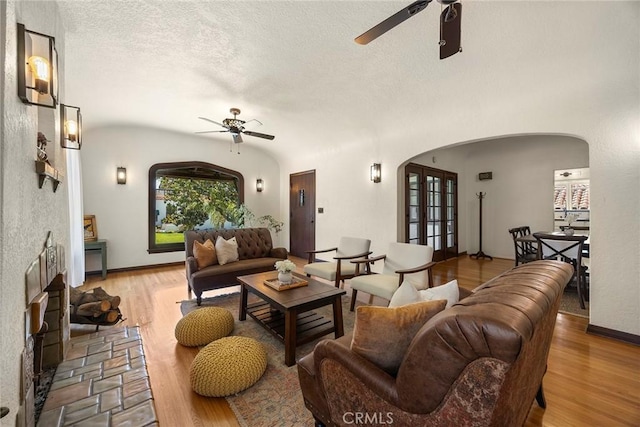 living area featuring arched walkways, a ceiling fan, and wood finished floors