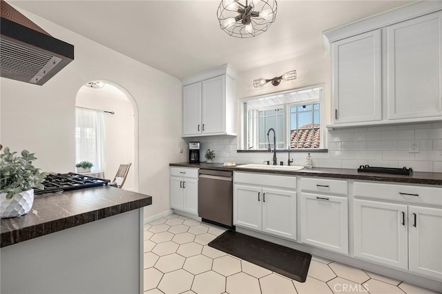 kitchen with decorative backsplash, dark countertops, dishwasher, a sink, and extractor fan