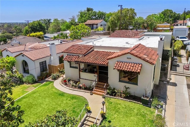 mediterranean / spanish-style house featuring fence, a tiled roof, stucco siding, and a front yard