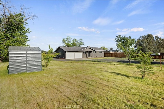 view of yard with a garage, fence, an outbuilding, and a storage unit