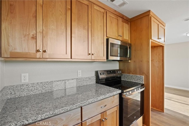 kitchen with visible vents, appliances with stainless steel finishes, light stone countertops, baseboards, and light wood finished floors