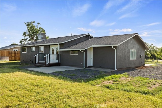 back of house with fence, a shingled roof, stucco siding, a patio area, and a lawn