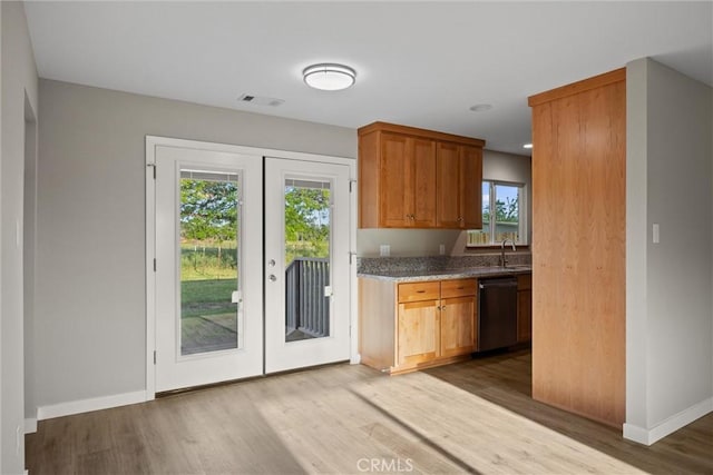 kitchen featuring stainless steel dishwasher, wood finished floors, baseboards, light stone counters, and a sink