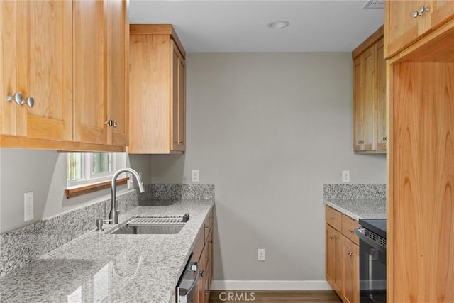 kitchen with light stone countertops, dishwasher, baseboards, a sink, and range