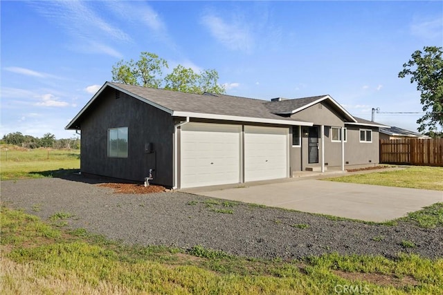 ranch-style house featuring a garage, fence, and driveway