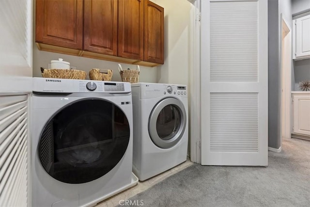 washroom featuring cabinet space, light colored carpet, and washing machine and clothes dryer