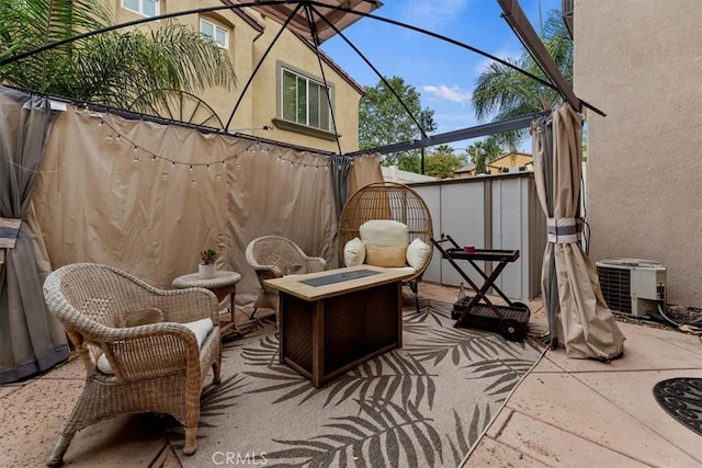 view of patio featuring fence, central AC unit, and an outdoor fire pit