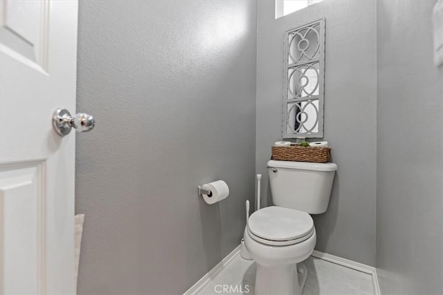 bathroom with baseboards, tile patterned flooring, and toilet