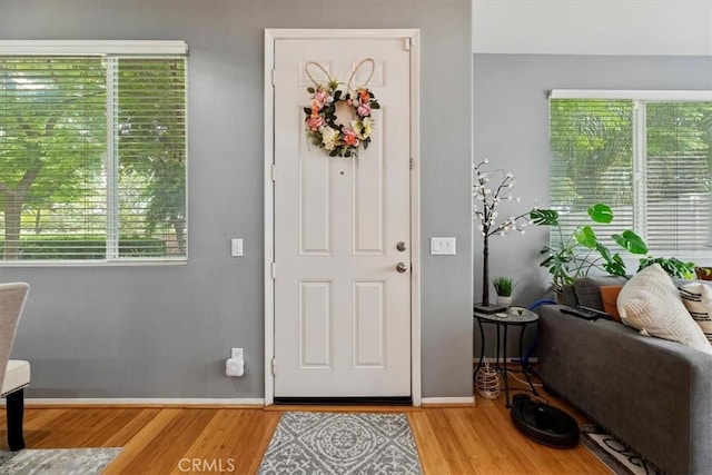 foyer entrance with baseboards, plenty of natural light, and light wood-style flooring