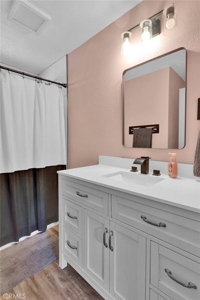 10634 Mesquite St, Oak Hills, CA 92344 - bathroom with a textured wall, curtained shower, wood finished floors, and vanity