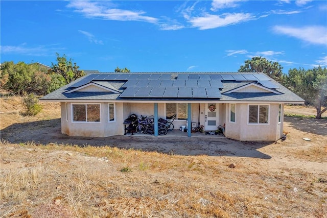10634 Mesquite St, Oak Hills, CA 92344 - back of property featuring a patio, a shingled roof, roof mounted solar panels, and stucco siding
