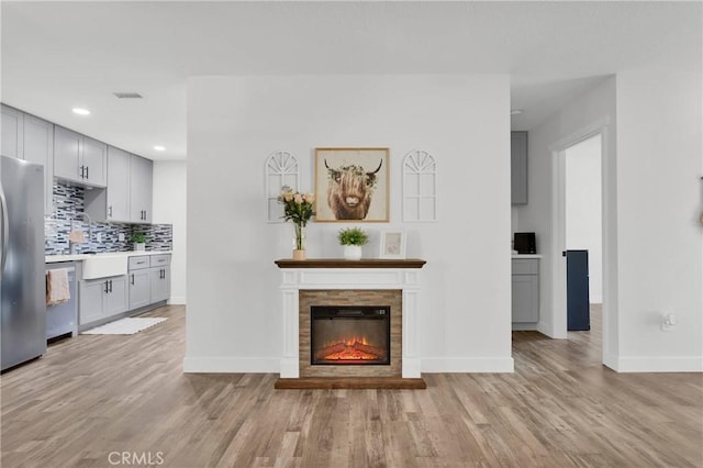 10634 Mesquite St, Oak Hills, CA 92344 - unfurnished living room featuring recessed lighting, baseboards, a glass covered fireplace, and light wood-style floors