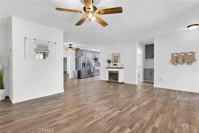 10634 Mesquite St, Oak Hills, CA 92344 - unfurnished living room featuring a ceiling fan, baseboards, a glass covered fireplace, and wood finished floors