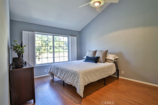 bedroom with baseboards, ceiling fan, wood finished floors, and lofted ceiling