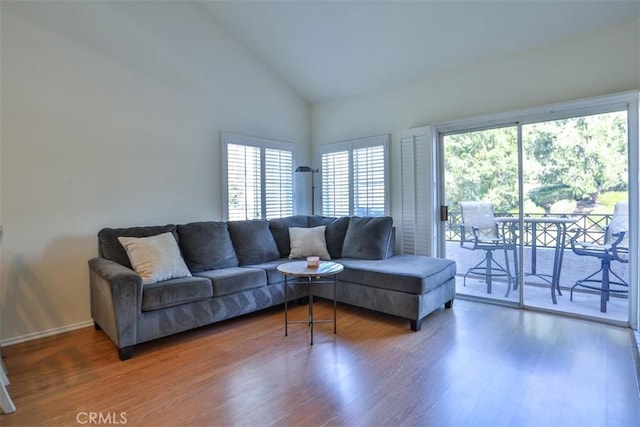 living room with high vaulted ceiling, baseboards, and wood finished floors