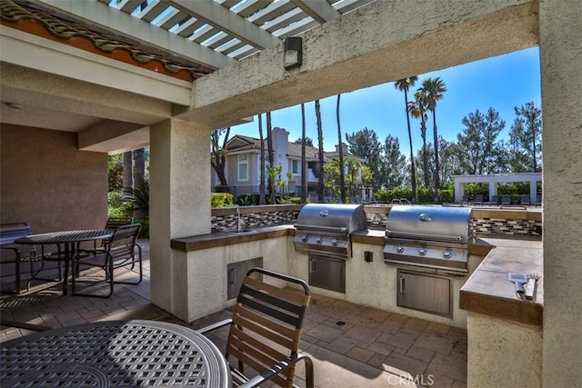 view of patio with a sink, an outdoor kitchen, a pergola, and a grill