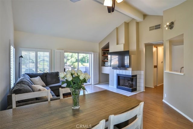 living area with a ceiling fan, visible vents, a fireplace, beam ceiling, and baseboards